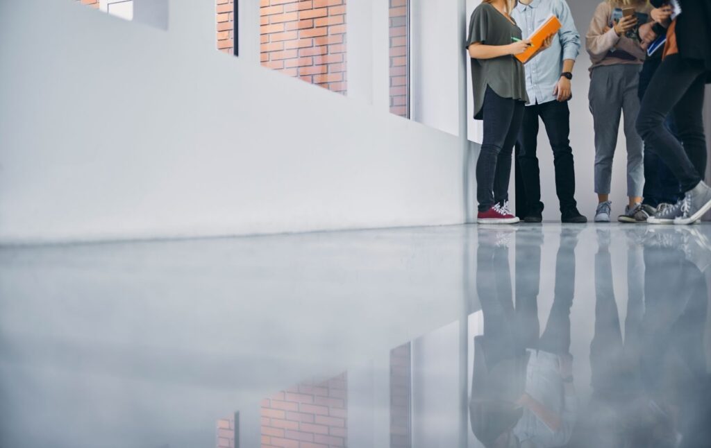 Students standing in a bright school hallway with smooth epoxy flooring