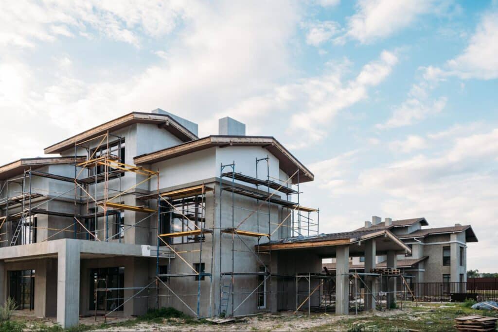 Modern house under construction with metal scaffolding on all sides.