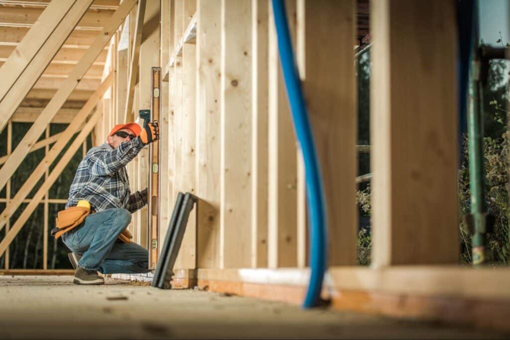 A builder ensures the straight alignment of wood posts using a bubble level